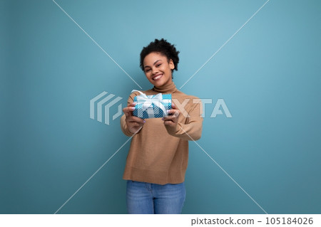young happy latin woman with curly hair rejoices with a birthday present and isolated studio 105184026