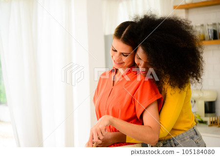 Happy lesbian couple cooking in kitchen at home, Women preparing dinner on first dating, Couple of female lovers spending time together at home, People with good relationship 105184080