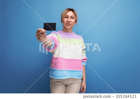 attractive blond woman in casual look demonstrating credit card mockup on blue background 105184121