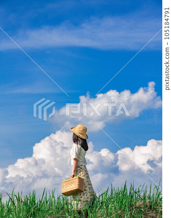 A young woman looking at the sky with a trunk under the summer blue sky and thunderheads 105184791