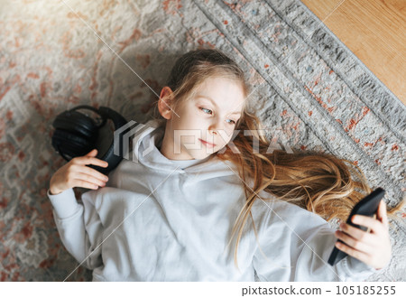 Little girl listening music lying on the floor 105185255