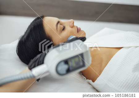Cosmetician doing laser resurfacing to client in  lying on couch in office 105186181