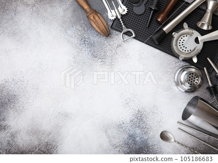 Steel cocktail shaker,strainer,jigger and wooden juicer with muddler on black rubber tray. Steel cocktail shaker,strainer,jigger and wooden juicer with muddler on black rubber tray. 105186683