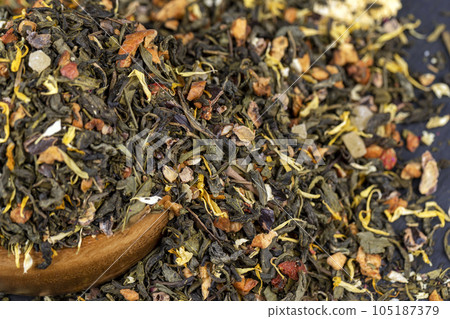 A large amount of dry green tea with pieces of fruit 105187379