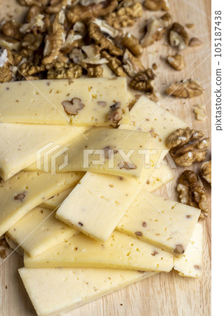 Sliced piece of milk cheese with walnuts 105187438