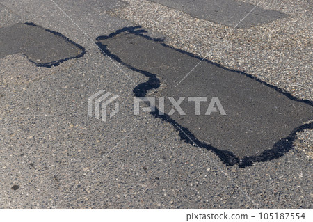 The repaired part of an asphalt road with patches 105187554