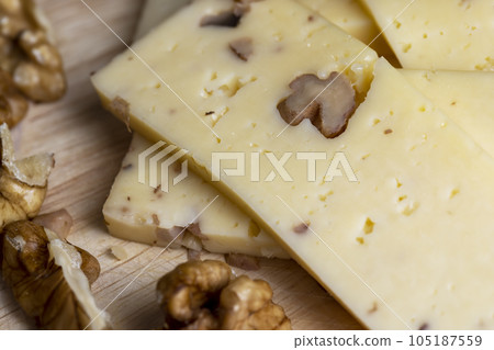 Sliced piece of milk cheese with walnuts Sliced piece of milk cheese with walnuts 105187559