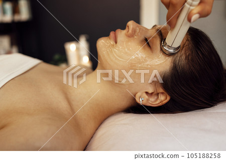 Closeup of face of beautiful relaxing girl undergoing hardware cosmetology procedure in spa Closeup of face of beautiful relaxing girl undergoing hardware cosmetology procedure in spa 105188258