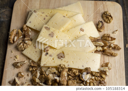 Sliced piece of milk cheese with walnuts Sliced piece of milk cheese with walnuts 105188314