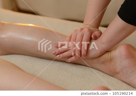 Woman receiving foot massage at beauty salon, calf massage Woman receiving foot massage at beauty salon, calf massage 105190214