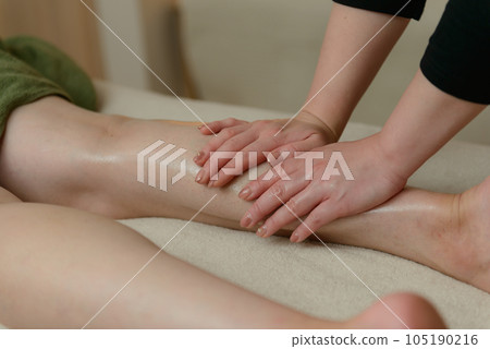 Woman receiving foot massage at beauty salon, calf massage 105190216