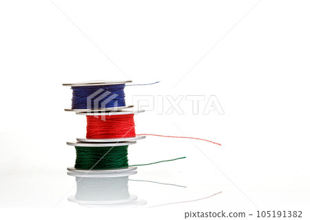 spools of thread in blue, red, green colors on a white background 105191382
