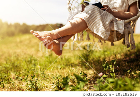 Women legs, barefoot girl sitting on swings in nature, outdoor on summer holiday Women legs, barefoot girl sitting on swings in nature, outdoor on summer holiday 105192619