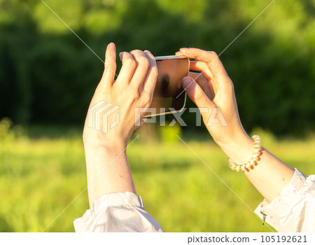 Hands holding mobile phone, taking photo, recording video in nature 105192621