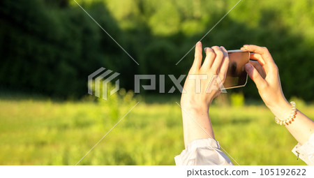 Hands holding mobile phone, taking photo outdoors. Banner background Hands holding mobile phone, taking photo outdoors. Banner background 105192622