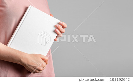 Holding book mockup, hardcover, white blank cover mock-up in hands. Banner background with copy space for text Holding book mockup, hardcover, white blank cover mock-up in hands. Banner background with copy space for text 105192642