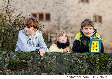 Little toddler girl and two kids boys holding selfmade lanterns with candle for St. Martin procession. Three Healthy children happy about family parade in kindergarten. German tradition Martinsumzug Little toddler girl and two kids boys holding selfmade lanterns with candle for St. Martin procession. Three Healthy children happy about family parade in kindergarten. German tradition Martinsumzug 105196046