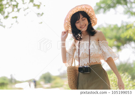 Portrait of asian young woman traveler with weaving hat and basket and a camera on green public park nature background. Journey trip lifestyle, world travel explorer or Asia summer tourism concept. Portrait of asian young woman traveler with weaving hat and basket and a camera on green public park nature background. Journey trip lifestyle, world travel explorer or Asia summer tourism concept. 105199053