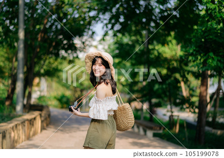 Portrait of asian young woman traveler with weaving hat and basket and a camera on green public park nature background. Journey trip lifestyle, world travel explorer or Asia summer tourism concept. Portrait of asian young woman traveler with weaving hat and basket and a camera on green public park nature background. Journey trip lifestyle, world travel explorer or Asia summer tourism concept. 105199078