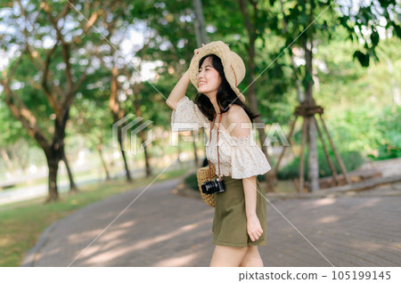 Portrait of asian young woman traveler with weaving hat and basket and a camera on green public park nature background. Journey trip lifestyle, world travel explorer or Asia summer tourism concept. Portrait of asian young woman traveler with weaving hat and basket and a camera on green public park nature background. Journey trip lifestyle, world travel explorer or Asia summer tourism concept. 105199145