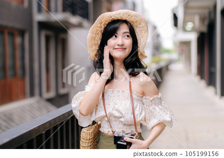 Happy youth asian woman with camera travels street city trip on leisure weekend. Young hipster female tourist sightseeing summer urban Bangkok destination. Asia summer tourism concept. Happy youth asian woman with camera travels street city trip on leisure weekend. Young hipster female tourist sightseeing summer urban Bangkok destination. Asia summer tourism concept. 105199156