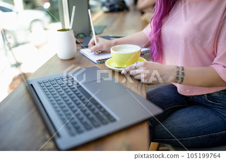 Woman typing on notebook with blank screen, sitting at wooden table 105199764