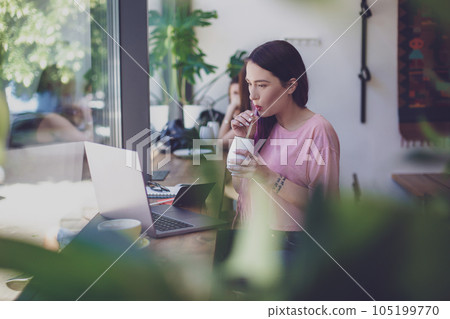 Side view of young businesswoman sitting at table in coffee shop 105199770