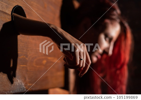 A redhead woman is imprisoned in a wooden pillory during sex games. BDSM Erotic fantasies.Subordination. Toys for adults. 105199869