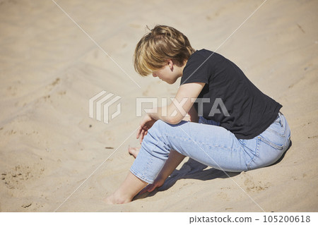 Teenage girl sitting on the beach in Denmark 105200618