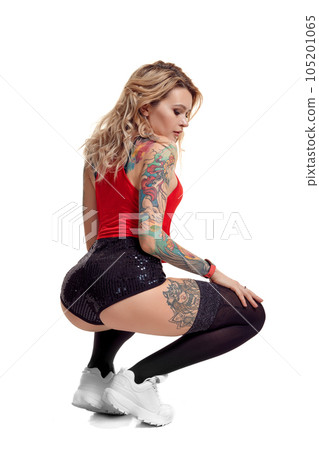 Sexy blond twerk woman with tattoed body and long curly hair is posing in studio. 105201065