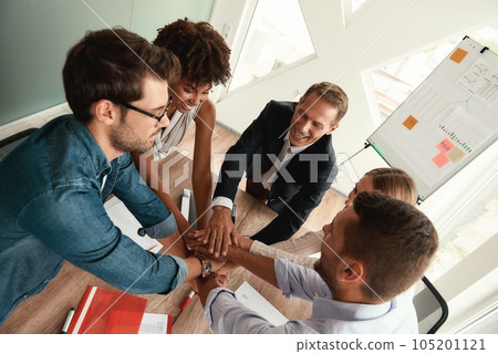Top view of business people holding hands together while sitting in the modern office 105201121