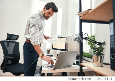 Multitasking. Side view of successful bearded trader or businessman in formal wear working with laptop while standing at his modern office. Multitasking. Side view of successful bearded trader or businessman in formal wear working with laptop while standing at his modern office. 105201141