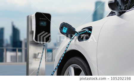 Electric car plugged in with charging station with city background. Peruse Electric car plugged in with charging station with city background. Peruse 105202198