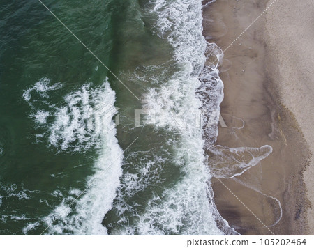 a stunning aerial view of the sea, with waves breaking against a sandy beach. a stunning aerial view of the sea, with waves breaking against a sandy beach. 105202464
