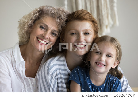 Happy girls and women of three generations sitting close together Happy girls and women of three generations sitting close together 105204707