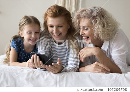 Positive kid girl, mom and grandma using smartphone together Positive kid girl, mom and grandma using smartphone together 105204708