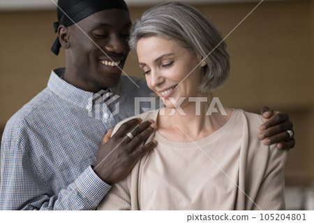 Happy handsome young African man hugging pretty grey haired girlfriend Happy handsome young African man hugging pretty grey haired girlfriend 105204801