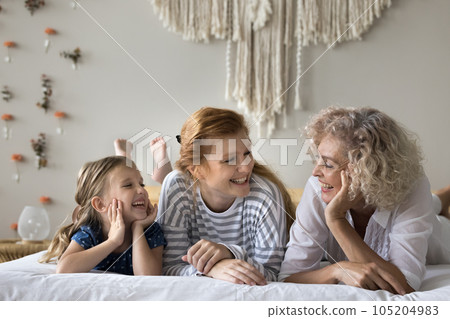Happy carefree kid, mother and grandmother relaxing on bed Happy carefree kid, mother and grandmother relaxing on bed 105204983