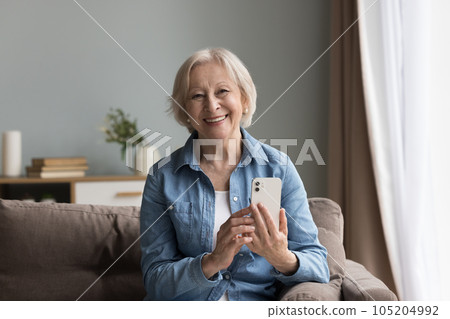 Portrait of attractive elderly woman pose for camera with cellphone 105204992