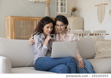 Focused mature mother and adult child woman sitting close together 105205055