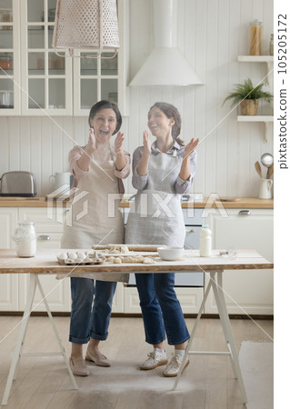 Happy retired mom and adult daughter in aprons baking together Happy retired mom and adult daughter in aprons baking together 105205172