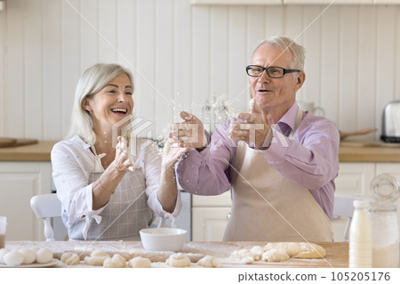 Positive active senior couple in aprons baking buns at home Positive active senior couple in aprons baking buns at home 105205176