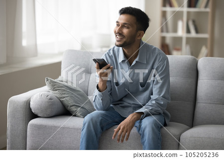 Cheerful attractive young Indian man speaking voice message Cheerful attractive young Indian man speaking voice message 105205236