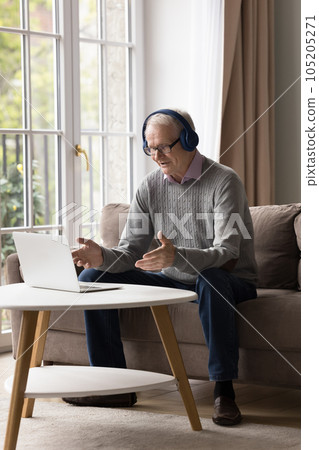 Elderly man in headphones talking through video call Elderly man in headphones talking through video call 105205271