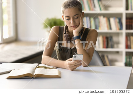 Focused pensive hipster student girl typing on mobile phone Focused pensive hipster student girl typing on mobile phone 105205272