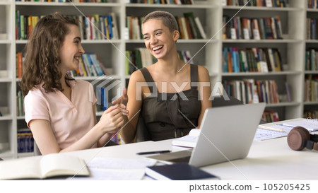 Two happy college girl friends having fun in campus library 105205425