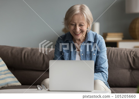 Senior woman laughs while watch videos or movie on laptop 105205660