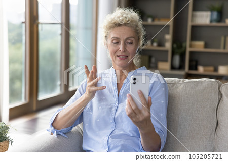 Positive beautiful blonde mature woman speaking on video call Positive beautiful blonde mature woman speaking on video call 105205721