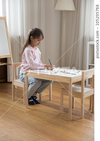 Focused cute little kid girl engaged in educational home activity 105205768