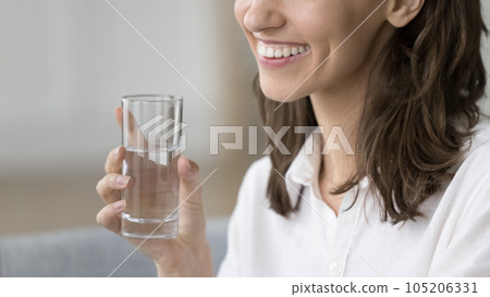Closeup cropped view beautiful young female holding glass of water Closeup cropped view beautiful young female holding glass of water 105206331